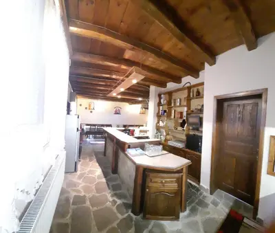 a kitchen with wooden ceilings and a stone floor at Костовският хан in Chepelare
