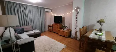 a living room with a couch and a tv and a table at The snug apartment near the brimming mountains in Bansko