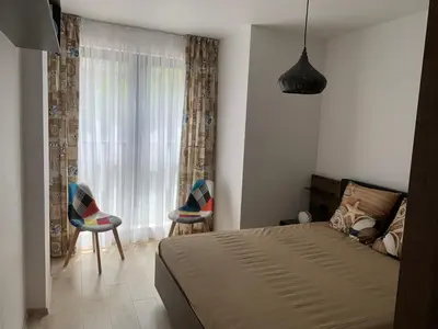 a bedroom with a bed and two chairs and a window at Kirmini apartment in Sofia