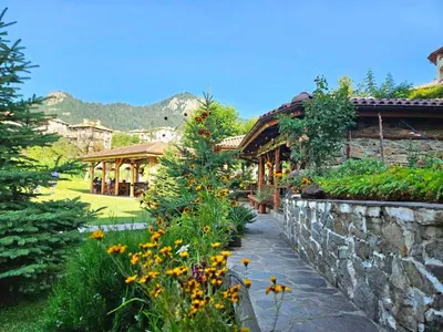 a garden with a stone wall and a building at SPA Apartament Daffi in Smolyan
