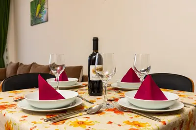 a table with plates and wine glasses with pink napkins at Yanevi Apartments at Grand Monastery Pamporovo in Pamporovo