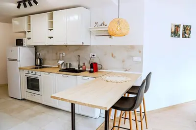 a kitchen with white cabinets and a wooden table at Sophie Studio - Top center, Cozy & Work-Friendly near AUBG, Free streaming platforms in Blagoevgrad