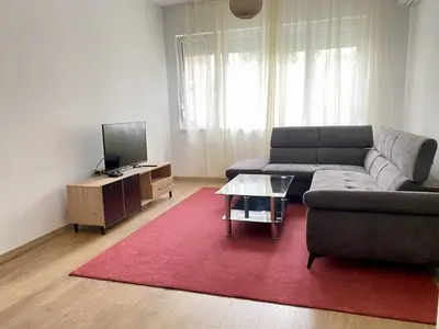 a living room with a couch and a red rug at Удобен апартамент в центъра на София in Sofia