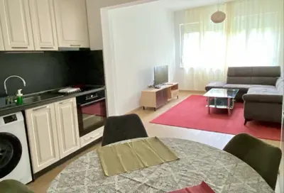 a kitchen and living room with a table and a couch at Удобен апартамент в центъра на София in Sofia