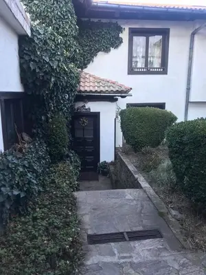 a white house with a black door and bushes at Matsureva House - Pri Ivan in Bansko