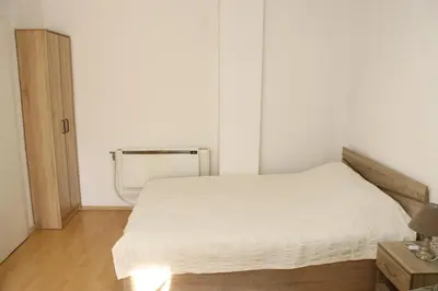 a bedroom with a white bed and a wooden floor at Apartment Nataliya in Smolyan