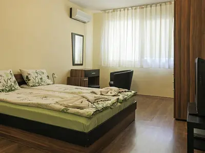 a bedroom with a bed with a television and a window at АПАРТАМЕНТ ЗА ГОСТИ 