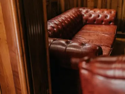 a brown leather couch in front of a mirror at The Castle - Your unique way of retreat in Borovets