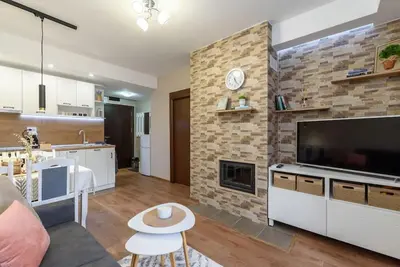 a living room with a large television and a brick wall at Vutovi's corner made with care in Bansko