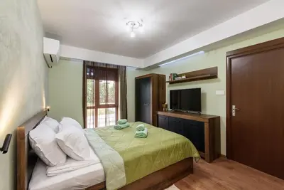 a bedroom with a bed with a green comforter and a television at Vutovi's corner made with care in Bansko