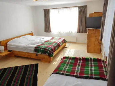 a bedroom with a bed and a window and two rugs at Калиновата къща in Stoykite