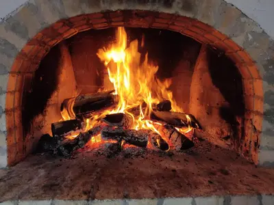 a brick oven with a fire in it at Калиновата къща in Stoykite
