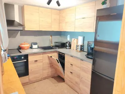 a kitchen with wooden cabinets and a black refrigerator at Калиновата къща in Stoykite