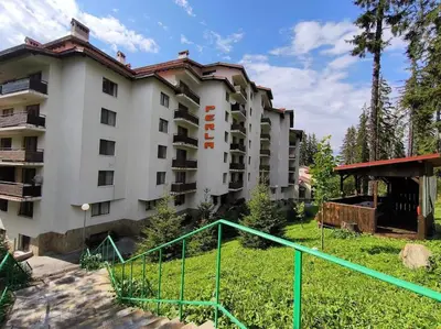a large white building with a green railing at Aпартамент Тити in Pamporovo