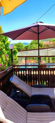 a bench sitting on a balcony with an umbrella at Guest house Elora in Chiflik