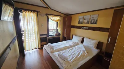 a bedroom with a bed with white sheets and pillows at Guest House Chepelare in Chepelare