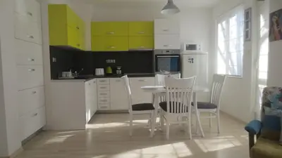 a kitchen with white cabinets and a table and chairs at Apartment Sophie in Plovdiv