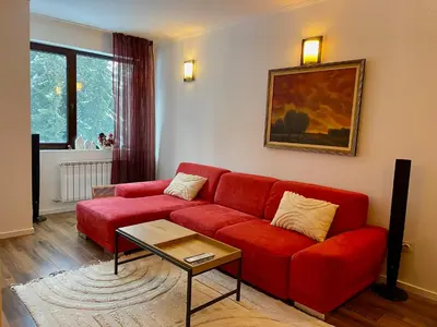 a living room with a red couch and a table at Stenata Boutique Apartments in Pamporovo