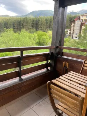 a wooden bench sitting on a balcony with a view at Forest View Apartment C34 Bansko in Bansko