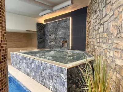 a jacuzzi tub in a room with a stone wall at 650m Ski in&out - Studio - FREE SPA and Parking in Bansko