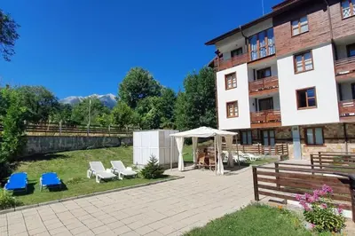 a building with a patio with chairs and a gazebo at Mountain Studio - Ski in and out - FREE Spa in Bansko