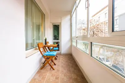 a balcony with a table and chairs and windows at Central Family Apt Fuzzy Muzzy 2 bedrooms MU University in Plovdiv