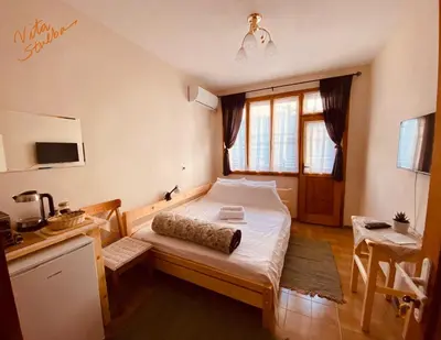 a bedroom with a bed and a table and a desk at Vita Stulba Guest House in Sandanski