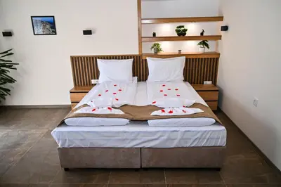 a bed with white sheets and red flowers on it at Къща Александра 2 in Dobrinishte