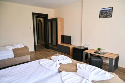 a room with two beds and a desk and a television at Къща Александра 2 in Dobrinishte