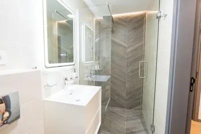a bathroom with a shower and a white sink and a mirror at Arni Aparts 1 in Velingrad