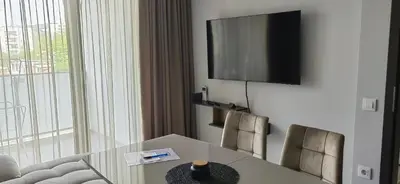 a room with a table and a television on a wall at Apartmenthaus Oborishte - 17 in Panagyurishte