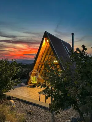 a small house with a roof on a wooden deck at Алпийска вила в полите Рила in Resilovo