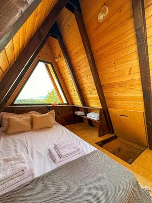 a bed in a wooden room with a window at Алпийска вила в полите Рила in Resilovo