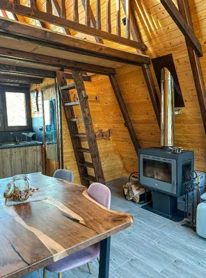 a wooden cabin with a wooden table and a stove at Алпийска вила в полите Рила in Resilovo