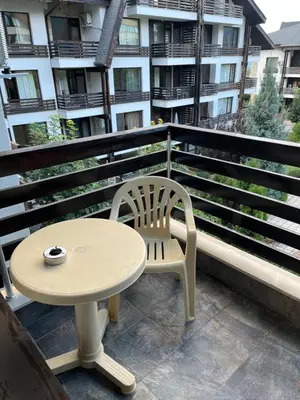 a table and a chair on a balcony with a building at Aspen Suites Студио Слънчев ден in Razlog