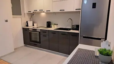 a kitchen with white cabinets and a stainless steel refrigerator at Apart Viki in Sandanski