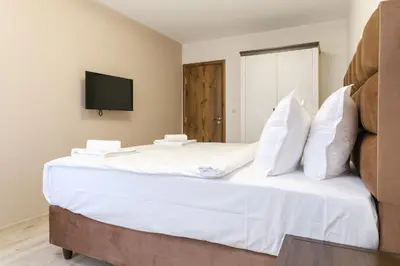 a large white bed with white pillows and a tv at LDV 13 1-Bedroom Apartments Free private parking in Plovdiv