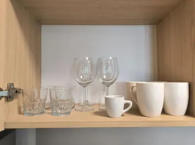 a shelf with wine glasses and cups on it at Spacious and modern apt, 6 guests, Central station, self check-in in Sofia