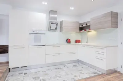 a white kitchen with white cabinets and a tile floor at Spacious and modern apt, 6 guests, Central station, self check-in in Sofia