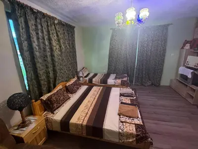 a bedroom with two beds and a chandelier at Пандова къща in Sandanski