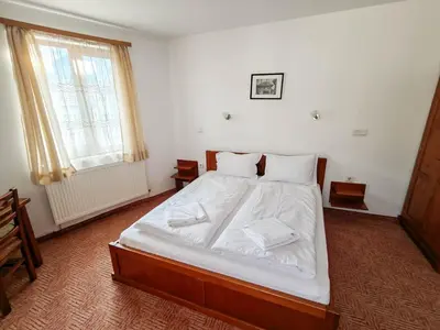 a bedroom with a bed with white sheets and a window at Todeva House Hotel and Tavern in Bansko
