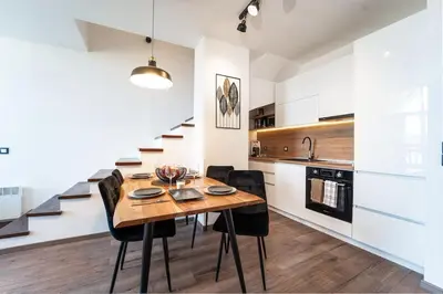 a kitchen and dining room with a wooden table and black chairs at Alpin Penthouse 2 Bedroom with Fireplace and Mountain View in Bansko