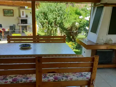 a wooden bench with a table in a yard at Kyurkchievi Guest House in Sapareva Banya