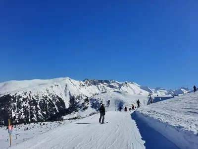 a group of people skiing down a snow covered mountain at Apartment in Aspen Golf in Bansko