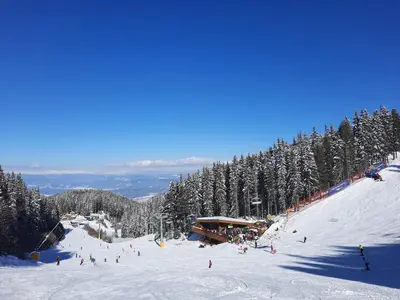 a group of people skiing down a snow covered ski slope at Apartment in Aspen Golf in Bansko