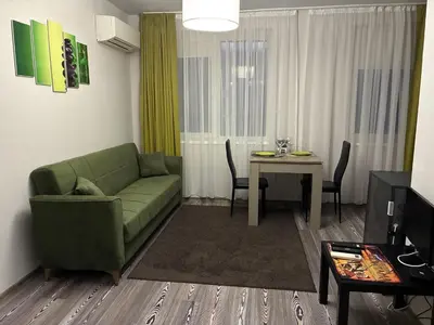 a living room with a green couch and a table at Апартамент Димана in Hisarya
