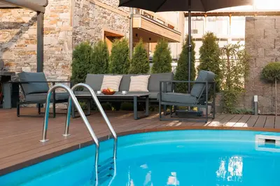 a pool with a table and chairs and an umbrella at Aqua Thermal Villa Banya in Banya