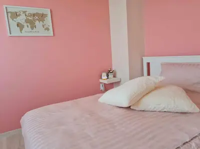 a bedroom with pink walls and a bed with two pillows at Домът на Билкарката in Plovdiv