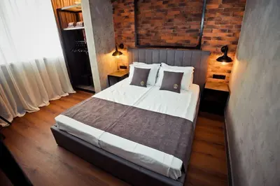 a bedroom with a large bed and a brick wall at AGIA 2 - cozy one room apartment in Sofia