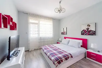 a bedroom with a large bed with a red headboard at Апартамент Веирас 2 in Velingrad